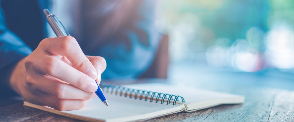 Business woman hand writing on a notepad with a pen in the office.Web banner.