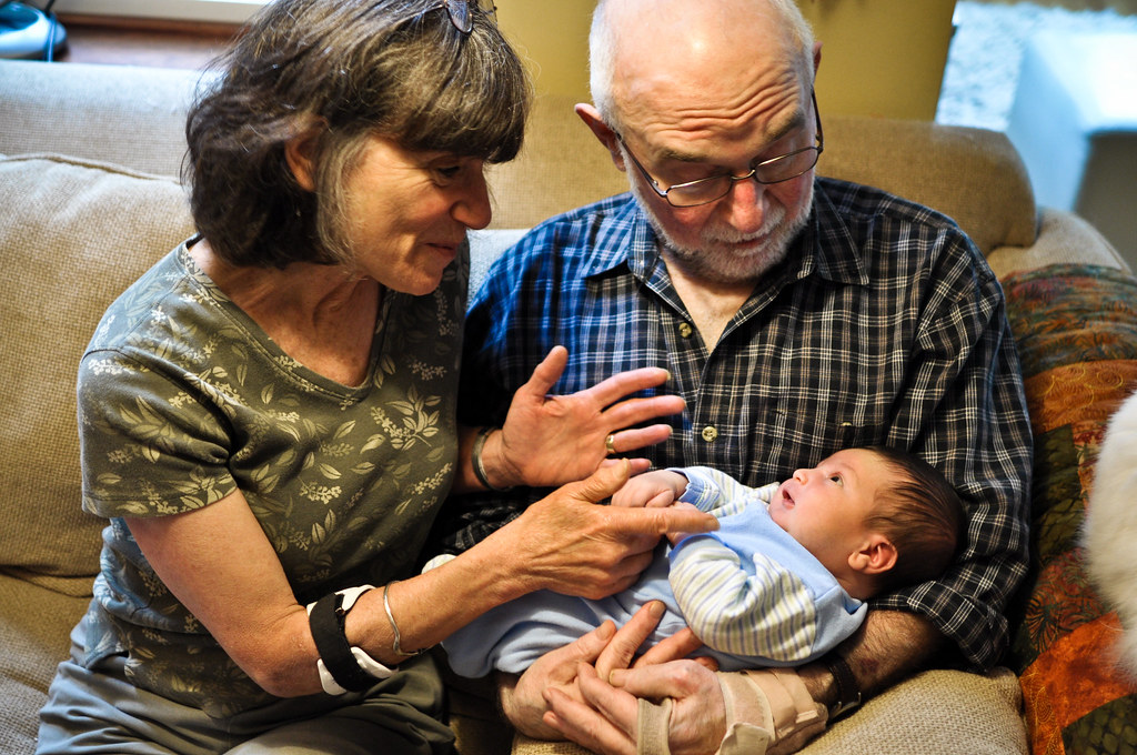 Two older humans hold a small infant.