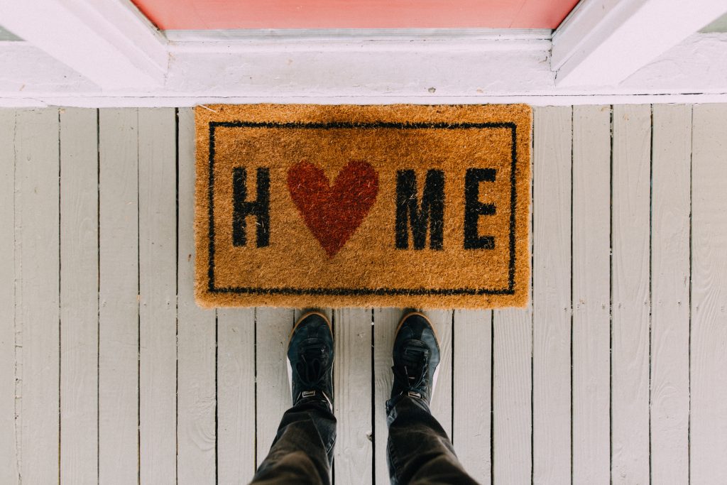 Photo of front entrance with door mat with the word Home. The o in home is replaced with a heart.