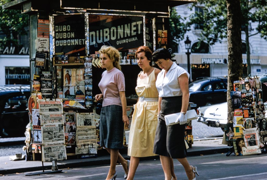 Women in front of a French kiosk selling magazines and newspapers.