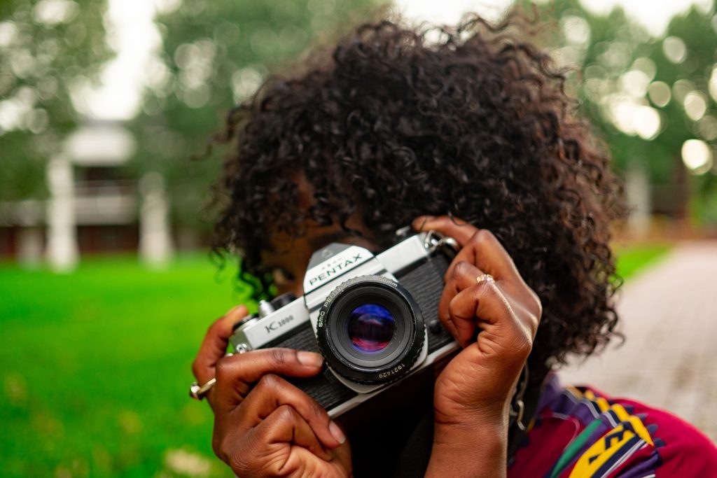 Woman taking picture and covering her face with vintage camera