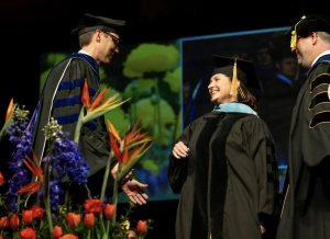 A graduate of the Ed.D. program in Educational Technology receives her doctoral hood from her advisor and then greets the Dean of the College of Education.