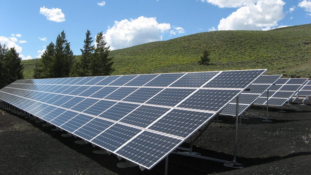 Solar panels in front of a rolling hills and blue sky background