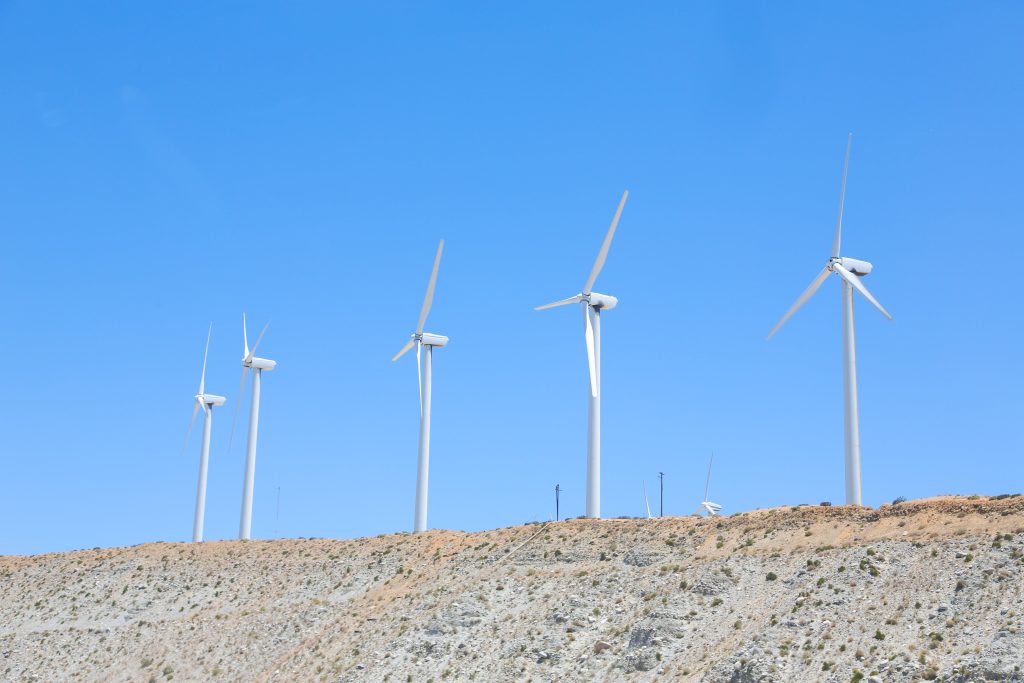 wind turbines in a row in the desert against a clear blue sky