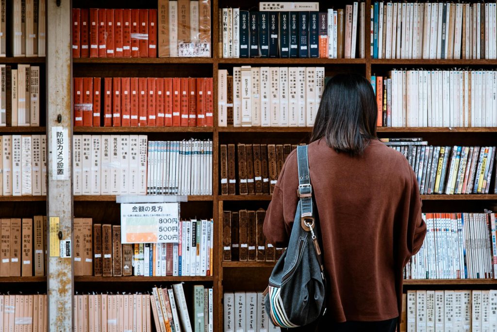 Girl in brown sweater looking for books in a library