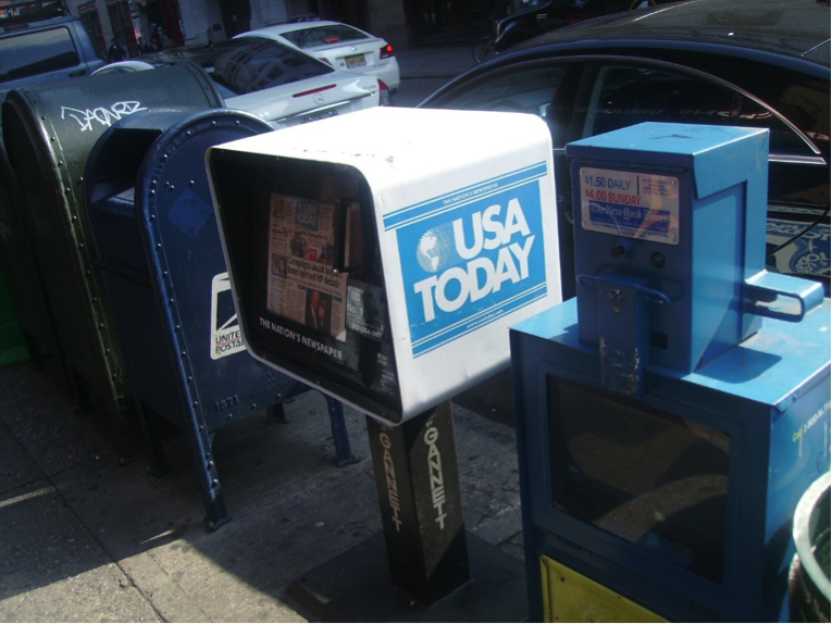 USA Today newspaper dispenser on street next to other newspaper dispensers