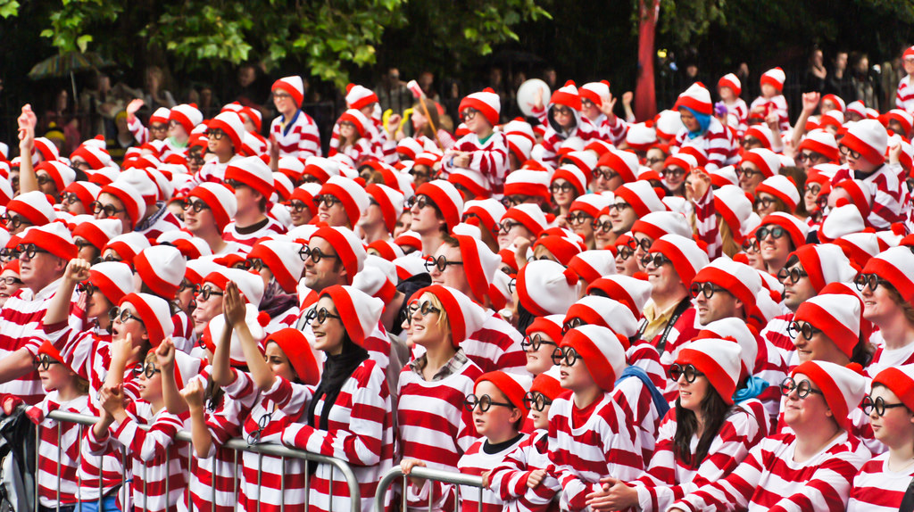 A large group of people all wearing red and white stripped hats and shirts and black rimmed glasses.