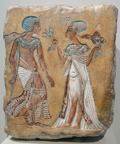 Carving on stone of an Egyptian man and a woman holdiing out flowers to him