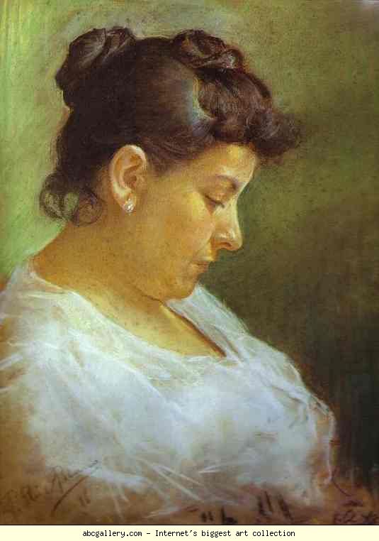 Woman with bun, pearl earrings, in white shirt looking down