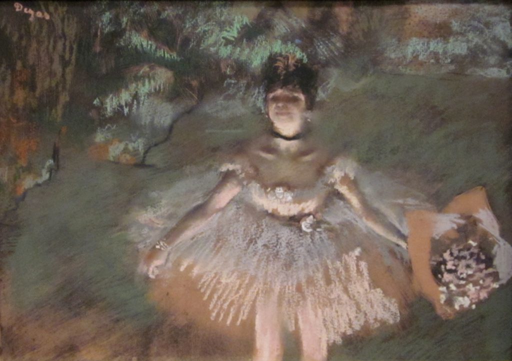 Ballerina in pink dress holding flower bouquet on a stage