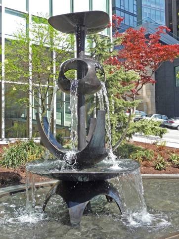 Fountain with water pouring from open sides of sphere onto a flower-like shape below