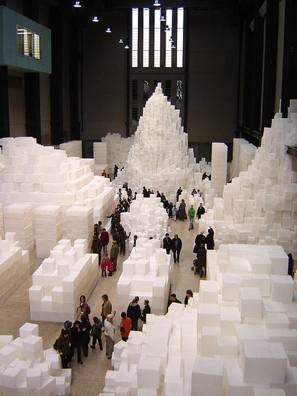 Various shapes made of large white bricks in a room with people looking