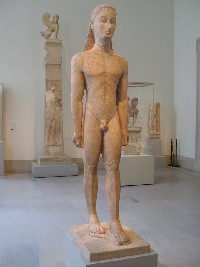 Stone statue of a naked man with one foot forward and long hair