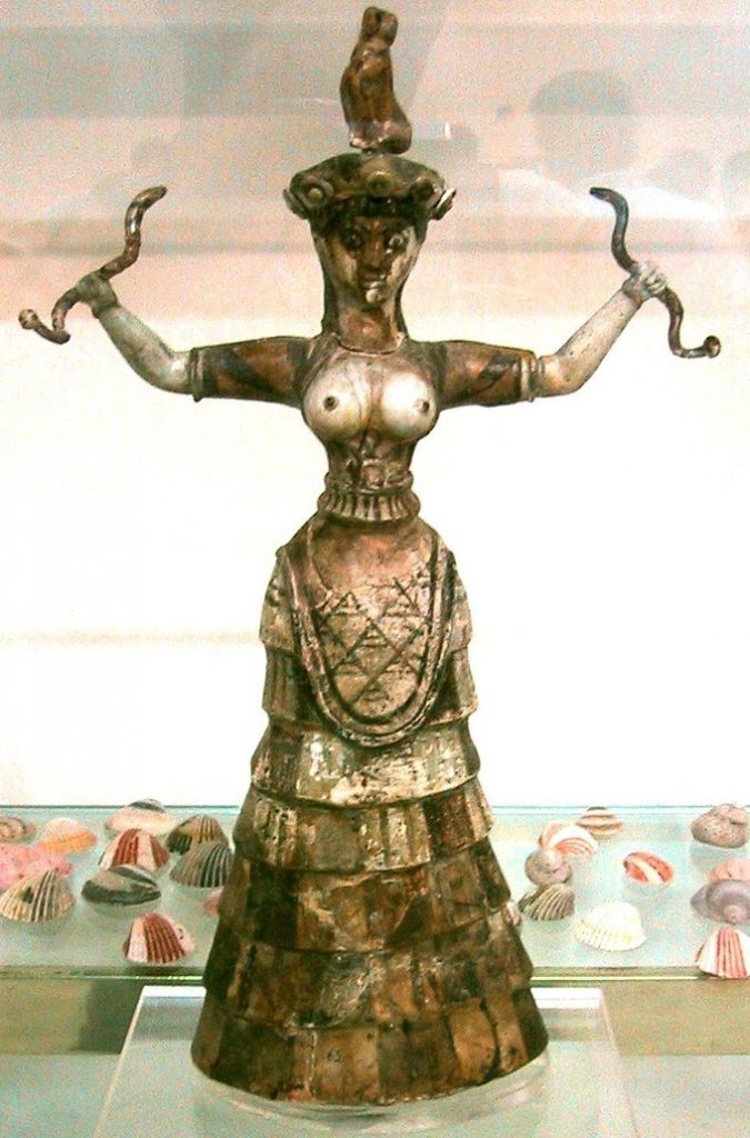 Gold colored woman with a rabbit on her head, a snake in each hand, and bare breasts