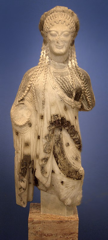 Stone statue of a woman with no legs, long curls, a smile, and a robe