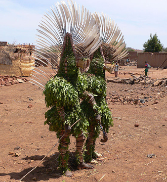 Two people dressed up in leaves with large feather headdresses