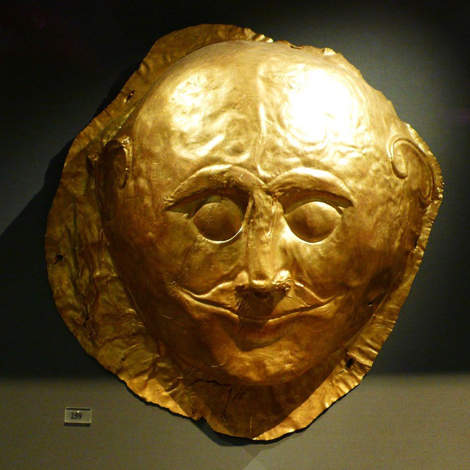 Golden face mask with slight smile and large eyebrows over closed eyes
