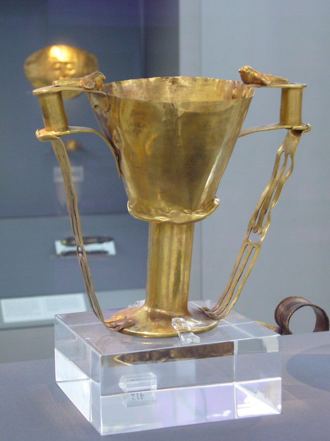 Golden cup on a glass stand with large handles from bottom to top
