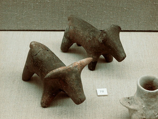 Two small, gray, cow-like figurines