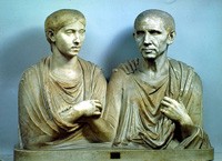 Two stone men in robes seated close and looking stern