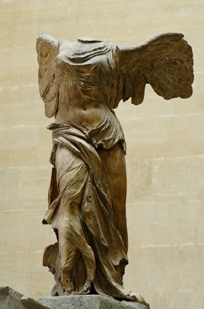 Headless winged stone statue of a woman in transparent gown
