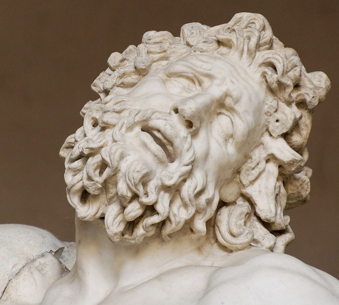 Face of a man with curly hair and beard, looking up in agony