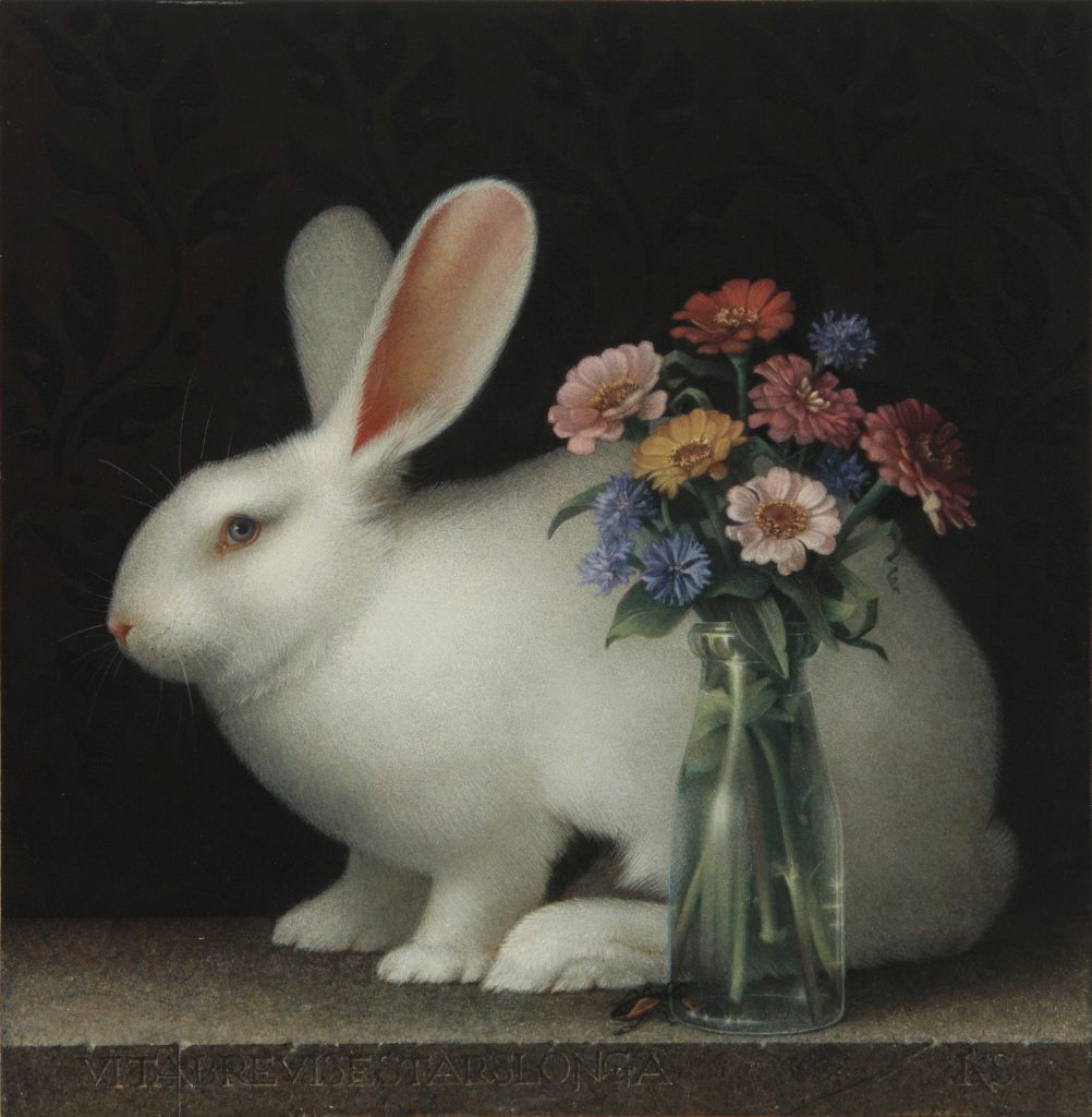 White rabbit crouched behind a vase with colorful zinnias