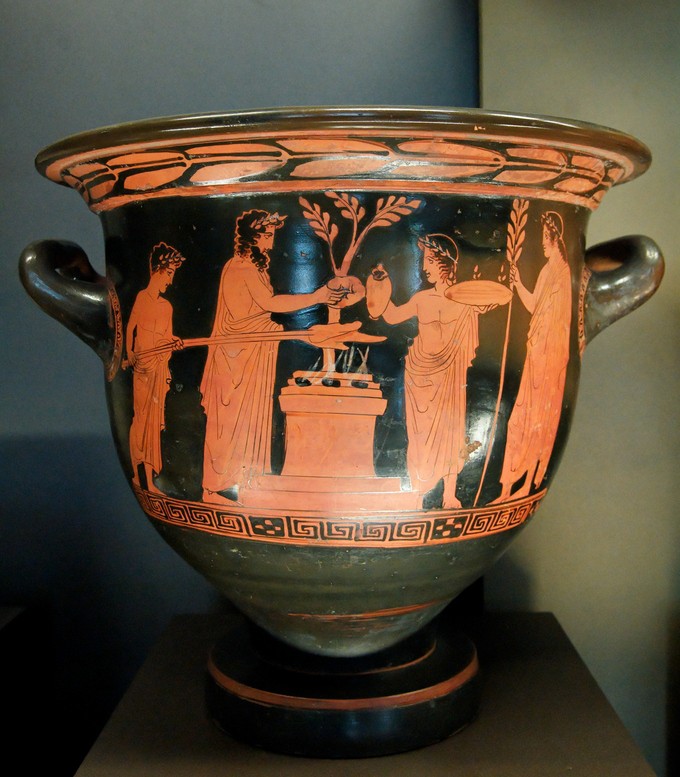Black bowl-shaped vase with brown figures around a tree sharing in a sacrifice
