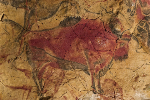 Painting of a bison in red on cracked yellow stone