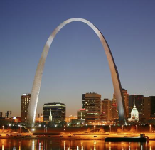 Giant arch against dusky blue sky over glowing city