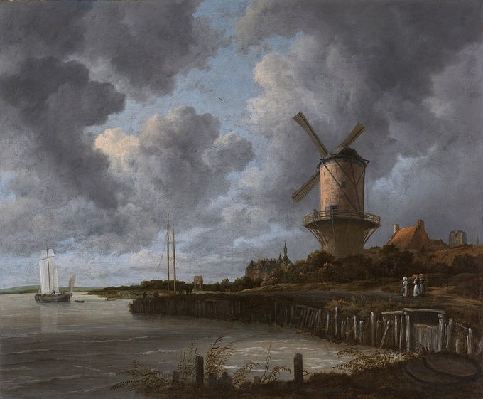 A windmill on the shore of a lake with a sailboat under a cloudy sky