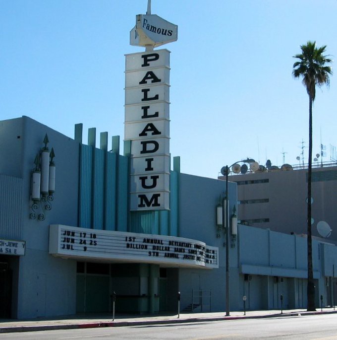 Theater building with tall sign that reads Famous Palladium near a palm tree