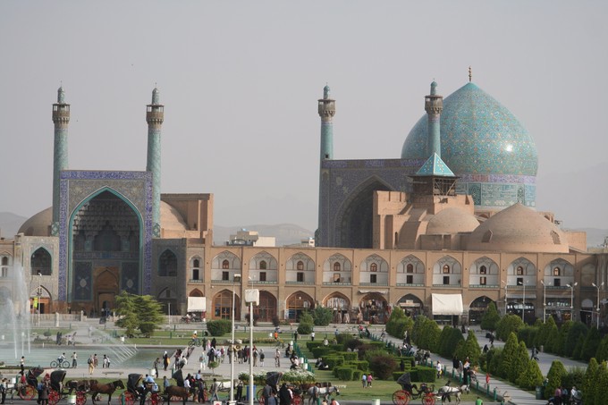 Building complex including a large blue dome and blue arched gates with many people in front