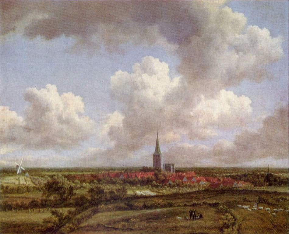 Tall church steeple and village in fields under a cloudy sky