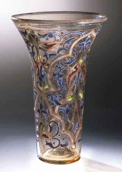 Tall slender vase covered in leaf shapes in blue, gold, and green