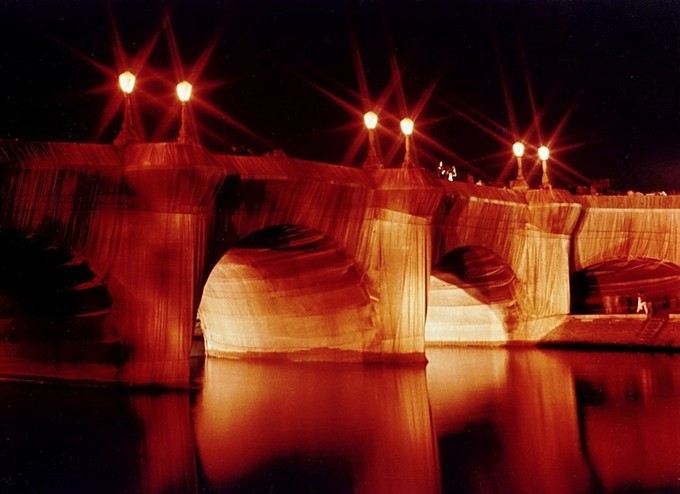 Arched bridge over still water under warm yellow lights