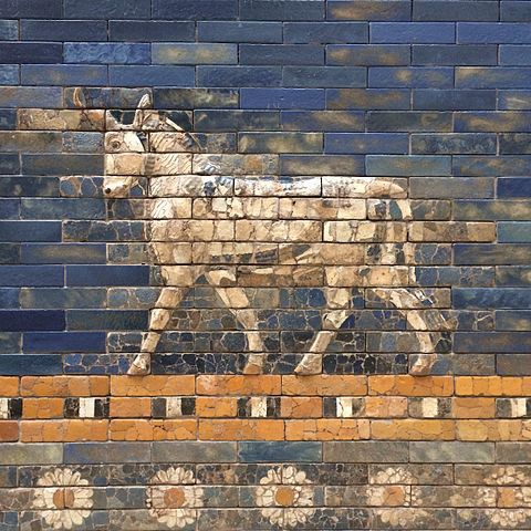 Brick wall painted blue with a donkey-like animal above a row of flowers