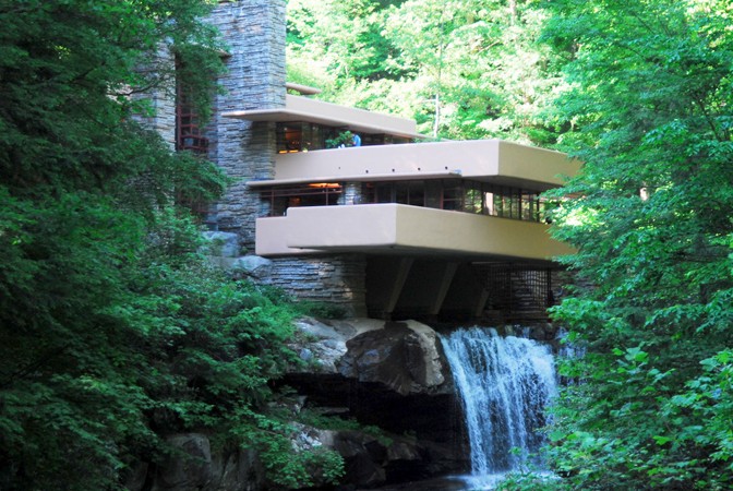 Square levels of a building on a mountainside above a man-made waterfall surrounded by trees