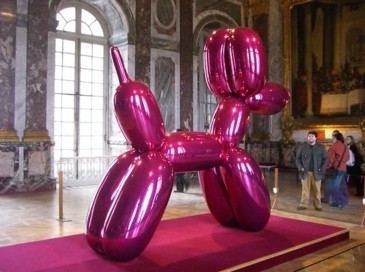Giant pink balloon dog in a museum with an audience