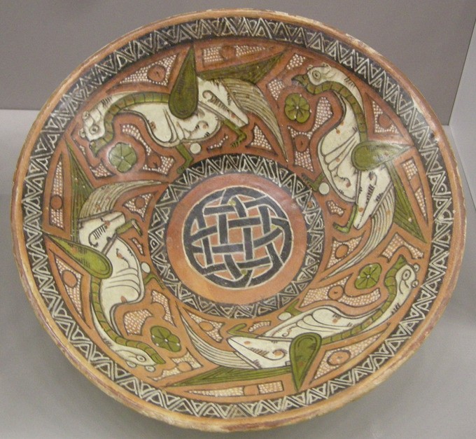 Brown bowl with a knot shape on the bottom and bird figures on the sides