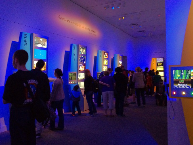 Crowds of people looking at screens in a dark room lit by blue lights