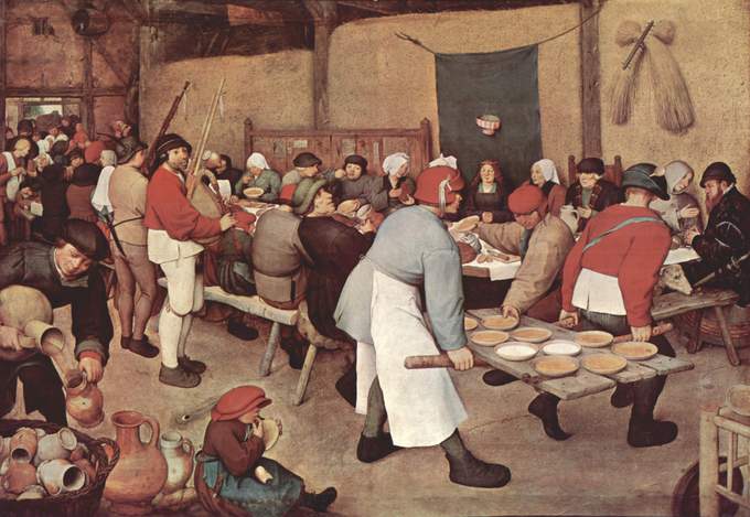 Crowds seated around tables while two men bring wooden boards with bowls of soup