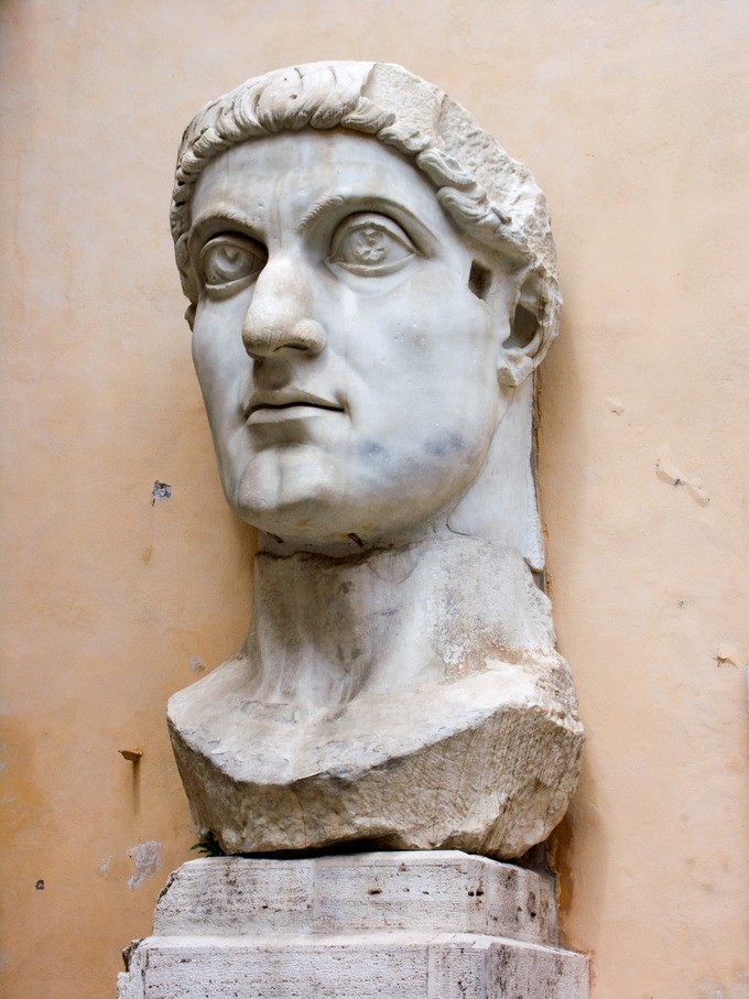 Stone head and neck of a man with large eyes and short hair