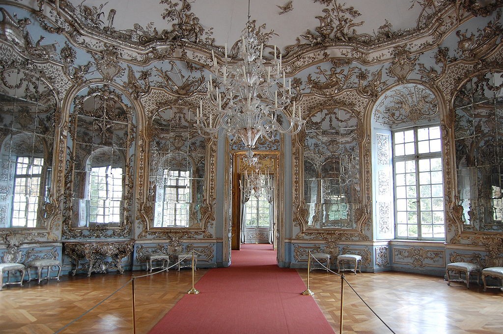 Large chandelier with blue and gold walls filled with many windows