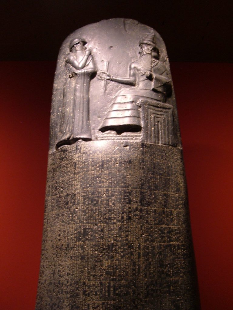Tall oblong stone with a king on his throne and another figure carved on top
