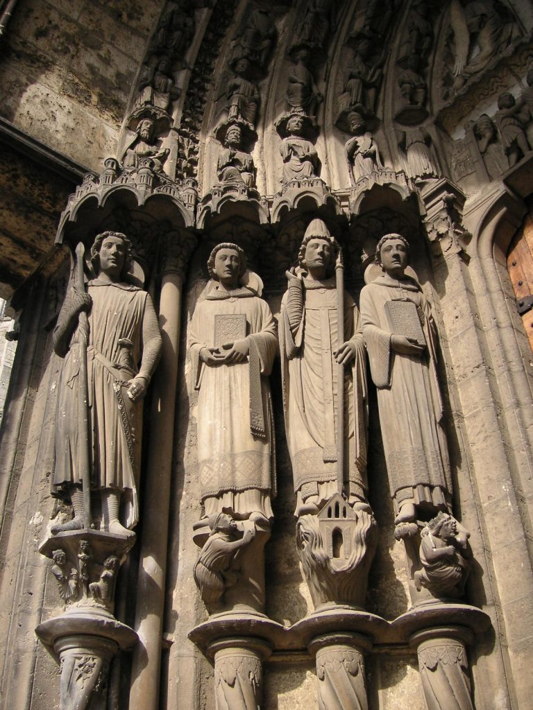 Four men in robes suspended on pillars looking down with houses and people beneath their feet