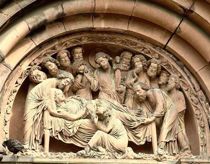 Stone statues of men surrounding a dying woman under an arch