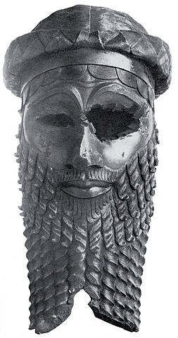 Gray stone head of a man with a large beard and a missing eye