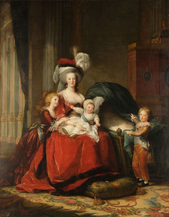 Woman with gray hair and a large hat holding a baby with two children beside her