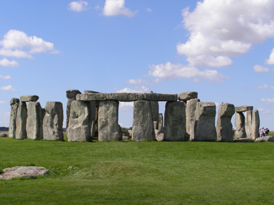 Row of giant stones standing on grass under blue sky